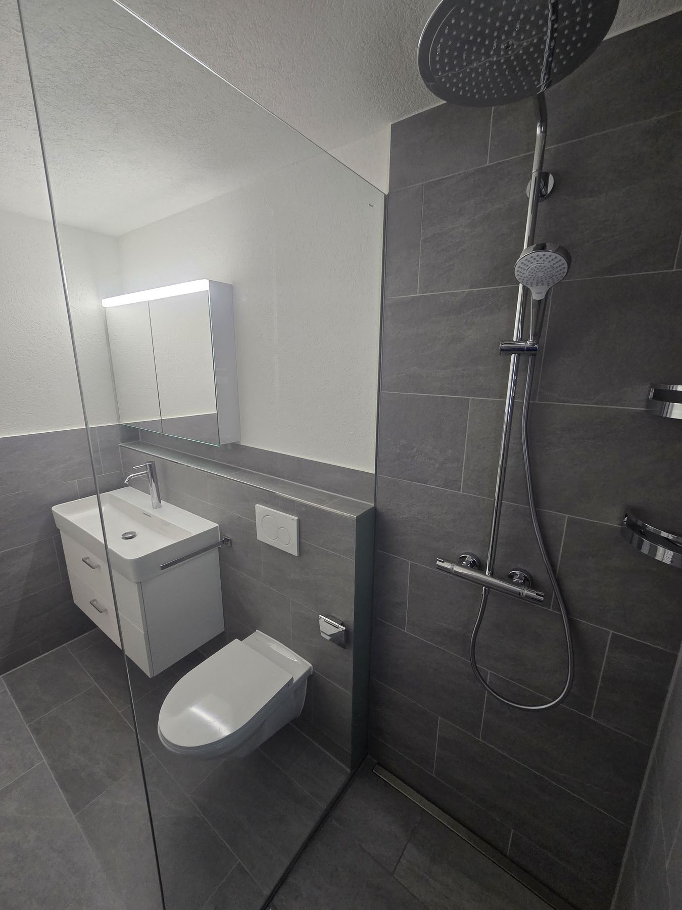 Dusche mit Regenbrause, Glaswand und Waschtisch mit Spiegelschrank